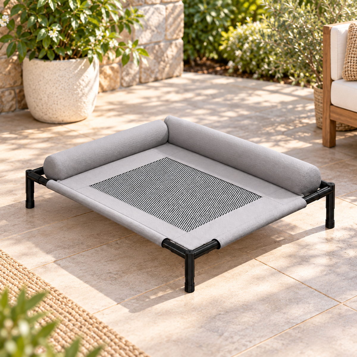 Raised cooling dog bed viewed from above on patio, showing grey bolster and mesh centre